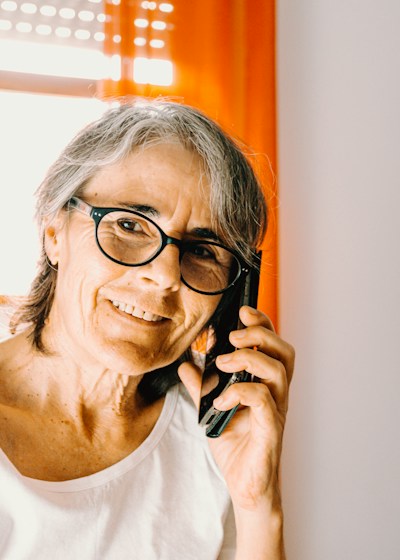An older woman smiling while talking on the phone